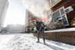A man cleans and clears the snow in front of the house on a sunny and frosty day. Cleaning the street from snow on a winter day. Snowfall, and a severe snowstorm in winter.