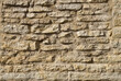 Texture of a beige stone wall. Smooth, cracked surface. Old castle wall of stone different shape. Part of a stone wall, for background or texture. 