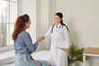 © Studio Romantic - Friendly female doctor shakes hands with her patient welcoming her to appointment in her office at medical clinic. Young female patient greets doctor while sitting on medical examination couch.