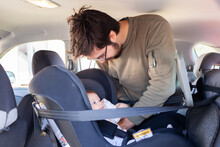 Young parent clicking baby into rear facing car seat