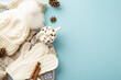 Winter concept. Top view photo of cup of hot drinking with marshmallow white knitted mittens headwear jumper pine cones anise cinnamon sticks on isolated light blue background with copyspace
