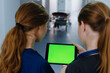 © makedonski2015 - Two female doctors look at the tablet screen with a green screen against the background of the clinic corridor.