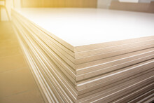 a stack of mdf panels neatly stacked in a cabinetry shop, background blurred with bokeh effect