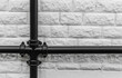 Big black vintage iron drainpipe against a solid white brick wall background.