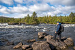 © Monika - Man hiking in forest near river and looking trough binoculars