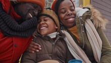 Medium Close-up Slowmo Of Lovely Black Man, Woman And Their Son Sitting Outdoors On Snowy Winter Day Hugging And Talking