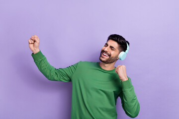 Wall Mural - Photo of good mood cheerful guy green long sleeve headphones singing favorite artist dancing fists up isolated on violet color background