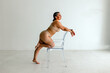 © Erin Brant/Stocksy - Curvy woman poses with clear chair