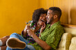 © Raymond Forbes LLC/Stocksy - Black Couple laughing enjoying martini on couch living room