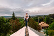 © ByLorena/Stocksy - Woman on top of roof holding security harness