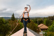 © ByLorena/Stocksy - Roofer woman on top of solar roof balancing