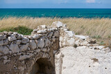 Ruiny kamiennych domów osady rybackiej w Gargano. Wybrzeże Adriatyku. W tle lazurowe morze i błękitne niebo.
