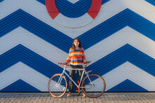 Woman With Bicycle Standing On The Background Of Blue Marine Wall 