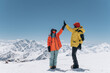 © Alina Hvostikova/Stocksy - Anonymous hikers giving high five in snowy mountains
