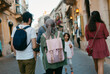 © Jimena Roquero/Stocksy - Group of people walking on sunny old town street in European city