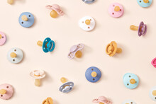Pattern Of Cute Colorful Pacifiers On Beige.