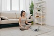 © SHOTPRIME STUDIO - Asian woman in tracksuit sits with laptop in lotus position at home and meditates with eyes closed with a slight smile, mental health support lifestyle