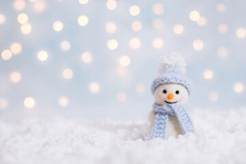 Snowman toy on a Christmas winter background with a copy space. Christmas and New Year greeting card. Snowman in a blue hat.