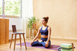 © ALTO IMAGES/Stocksy - Calm female practicing Padmasana yoga pose at home