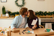 © BONNINSTUDIO/Stocksy - Loving couple kissing at table with Christmas gifts