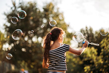 Girl Playing With Soap Bubbles In The Yard At Sunset