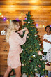 © BONNINSTUDIO/Stocksy - Blond woman decorating Christmas tree with girlfriends