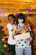 © BONNINSTUDIO/Stocksy - Merry women with box of Christmas decorations