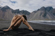 © Anastasia Mihaylova (Shpara)/Stocksy - Naked woman sitting on sand near the sea in front of mountains Iceland