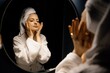© Vladimir Tsarkov/Stocksy - Young woman touching face near mirror