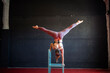 © Albert Martinez/Stocksy - Anonymous circus woman doing an inverted handstand on a chair.