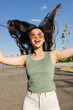 © VICTOR TORRES/Stocksy - Happy chinese woman in sunglasses waving dark long hair