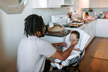 A father feeding his baby boy in a high chair