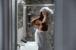 © David Prado/Stocksy - Black woman in towels standing in bathroom