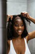 © David Prado/Stocksy - Smiling black woman putting on wig