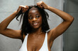 © David Prado/Stocksy - Smiling black woman putting on wig