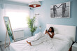 © David Prado/Stocksy - Black woman browsing smartphone on bed