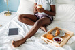 © David Prado/Stocksy - Unrecognizable woman with coffee on bed