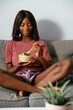 © David Prado/Stocksy - Cheerful black woman eating poke bowl