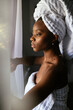 © David Prado/Stocksy - Black woman in towel looking out window