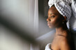 © David Prado/Stocksy - Black woman in towel looking out window