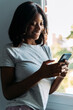 © David Prado/Stocksy - Smiling black woman using smartphone