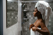 © David Prado/Stocksy - Black woman in towels standing in bathroom