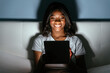 © David Prado/Stocksy - Smiling black woman with tablet