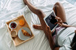 © David Prado/Stocksy - Unrecognizable woman browsing tablet on bed