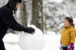 © Lauren Lee/Stocksy - Family building a snowman