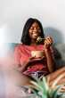 © David Prado/Stocksy - Cheerful black woman eating poke bowl