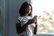 © David Prado/Stocksy - Smiling black woman using smartphone