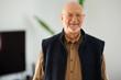 © Guille Faingold/Stocksy - Smiling bald pensioner in living room.