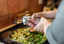 Close-up Photo Of Woman Cooking Lunch, Squeezing Garlic With Garlic Press Over Frying Pan