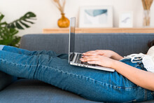 Close Up View Of A Woman Using A Laptop Lying On A Sofa.